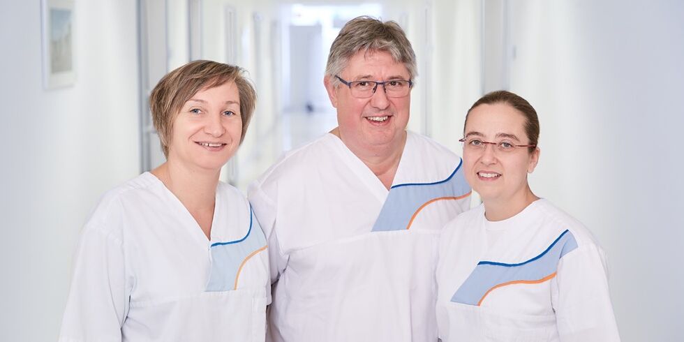 Team der familiären Pflege. Dieses besteht aus zwei Krankenpflegerinnen und einem Krankenpfleger, welcher sich auf diesem Foto in der Mitte zwischen den beiden befindet. 