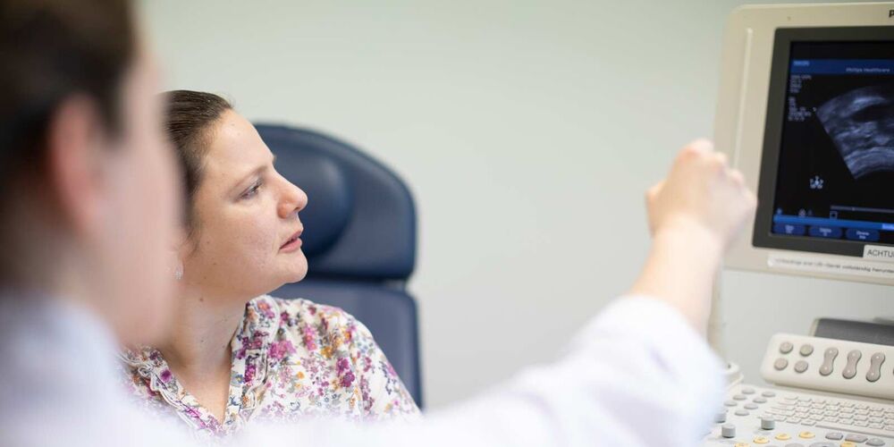 Zwei Frauen schauen auf einen Computer auf dem ein Ultraschall zu sehen. Die Ärztin zeigt der Patientin etwas auf diesem.