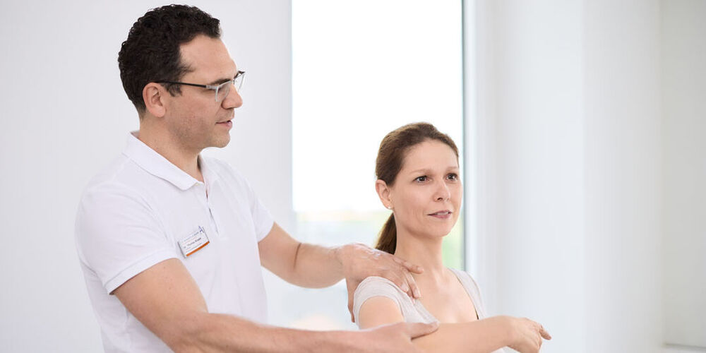 Dr. Kruppa untersucht die Schulter einer Patientin.