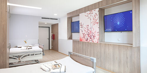 Modernes Zimmer mit zwei Einzelbetten und jeweils einem großen Fernseher. 
