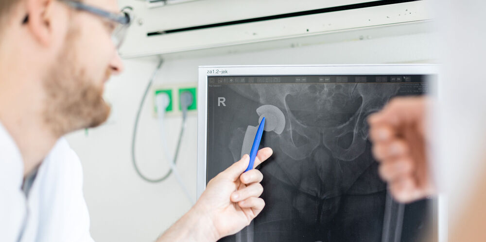 Ein Arzt aus dem Fachbereich Orthopädie erklärt eine Behandlung am Gelenk.