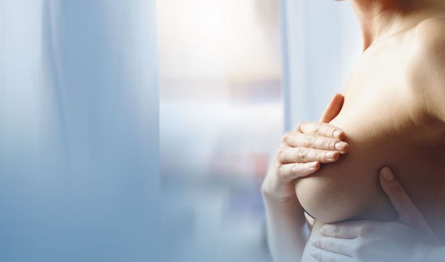Eine Frau, die ihre Brust abtastet, repräsentiert eine typische Patientin in der Gynäkologie.
