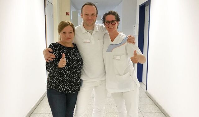Team der Notfallpflege, welches aus zwei Frauen und einem Mann besteht. Die drei schauen in die Kamera und lächeln. Die beiden Frauen außen zeigen einen Daumen nach oben.