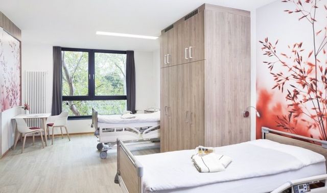 Patientenzimmer in der Klinik Neuwerk. In diesem stehen zwei Betten und ein Schrank, sowie ein Tisch mit zwei Stühlen.