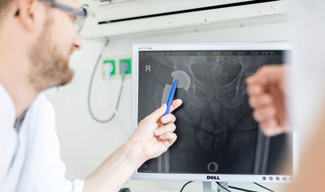 Bild eines Beckens auf einem Computerbildschirm. Ein Arzt zeigt mit einem Stift etwas auf diesem.