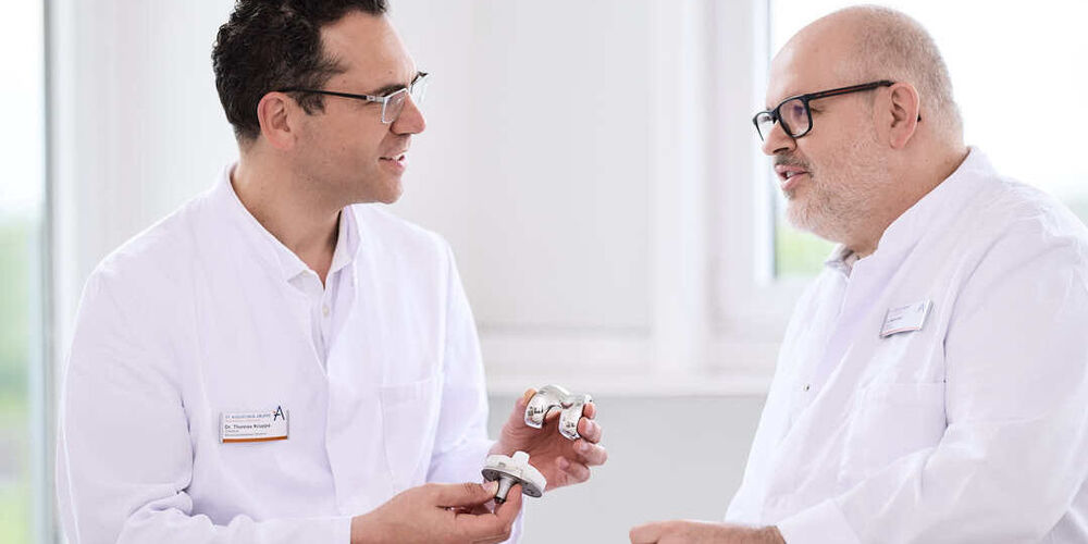 Zwei Ärzte schauen sich gemeinsam das Modell eines Knies an.